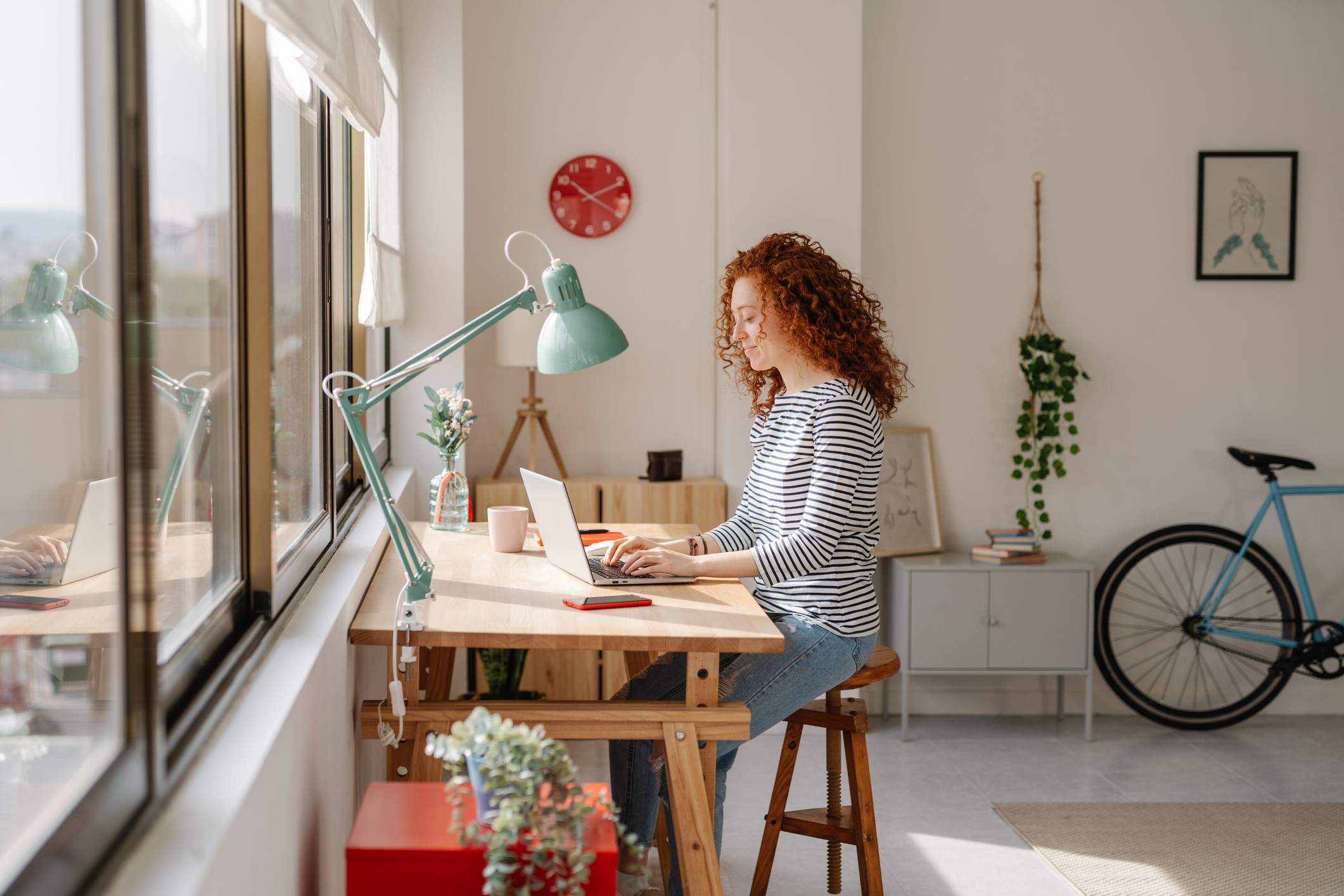 Woman-sitting-on-a-desk-using-a-laptop-computer-while-working-from-home-reentering-the-workforce