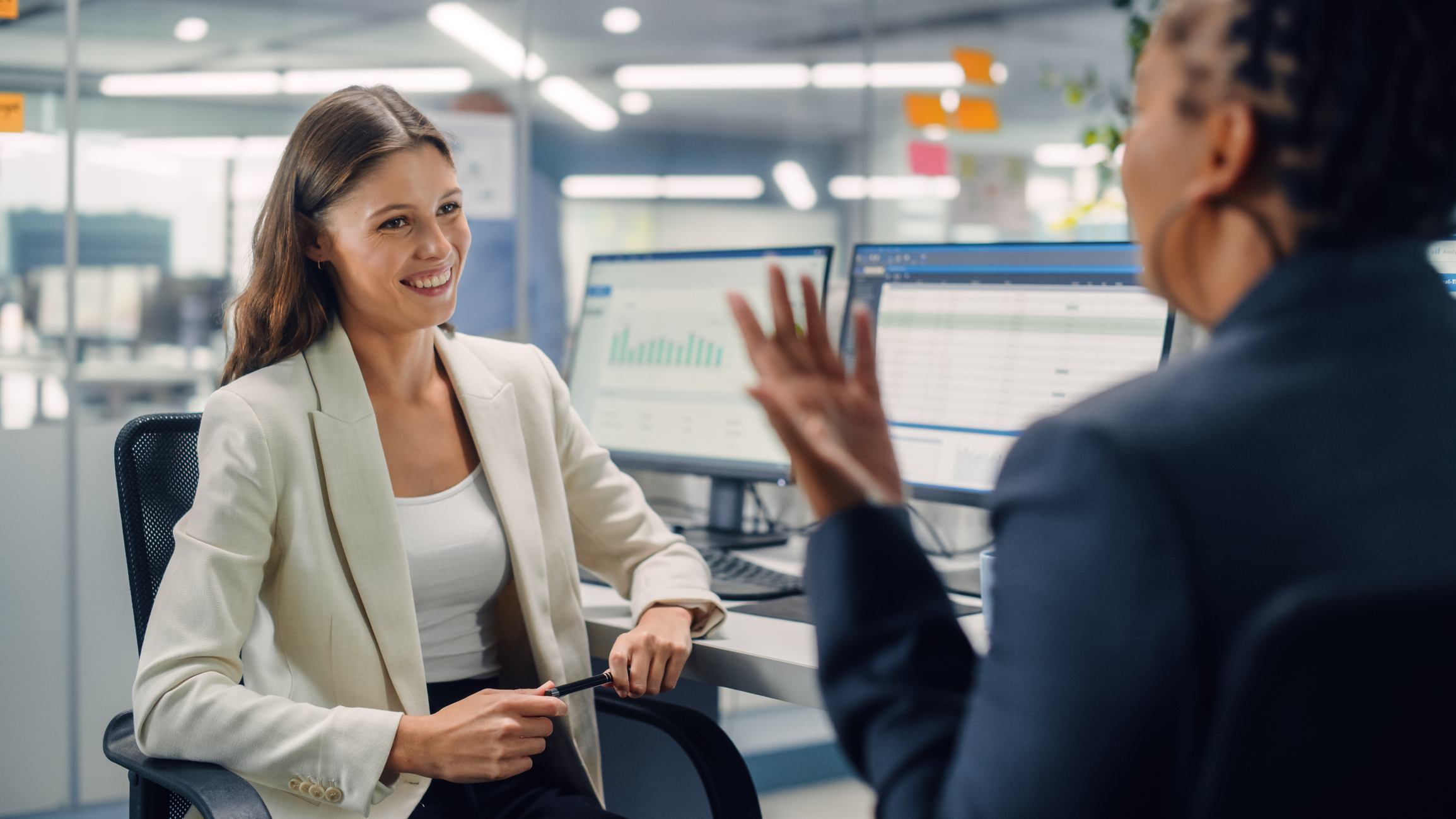 Woman-smiling-and-talking-to-coworker-at-office-how-to-congratulate-someone-on-a-promotion