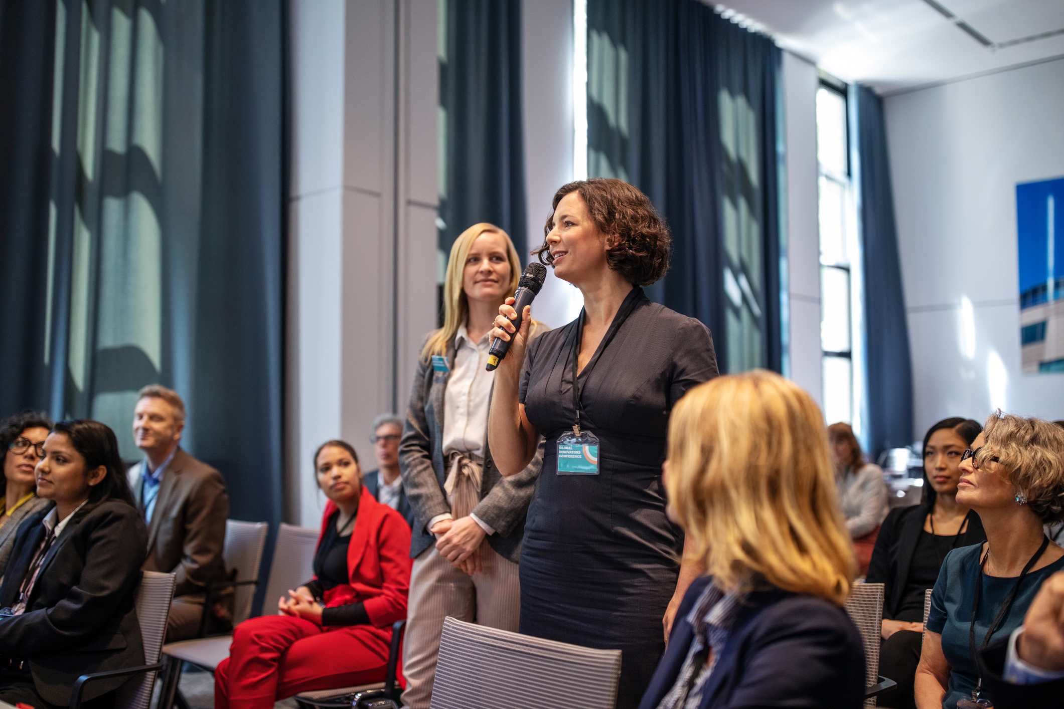 Woman-standing-at-work-meeting-with-microphone-asking-something-team-collaboration