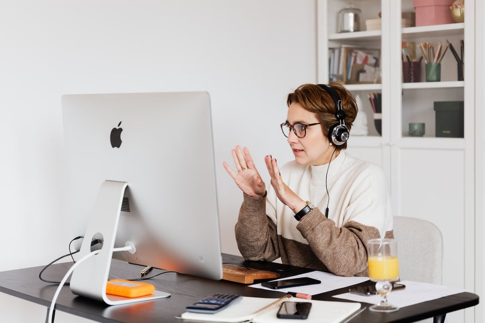 Woman-talking-seriously-to-computer-at-video-conference-with-headphones-on-virtual-interview