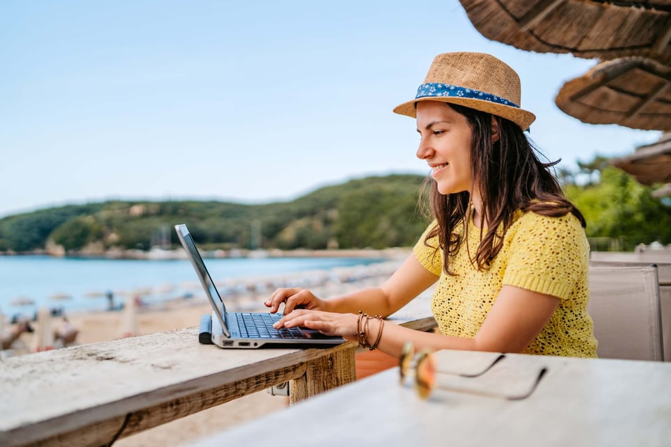 Woman-with-hat-at-the-beach-writing-email-on-laptop-out-of-office-message