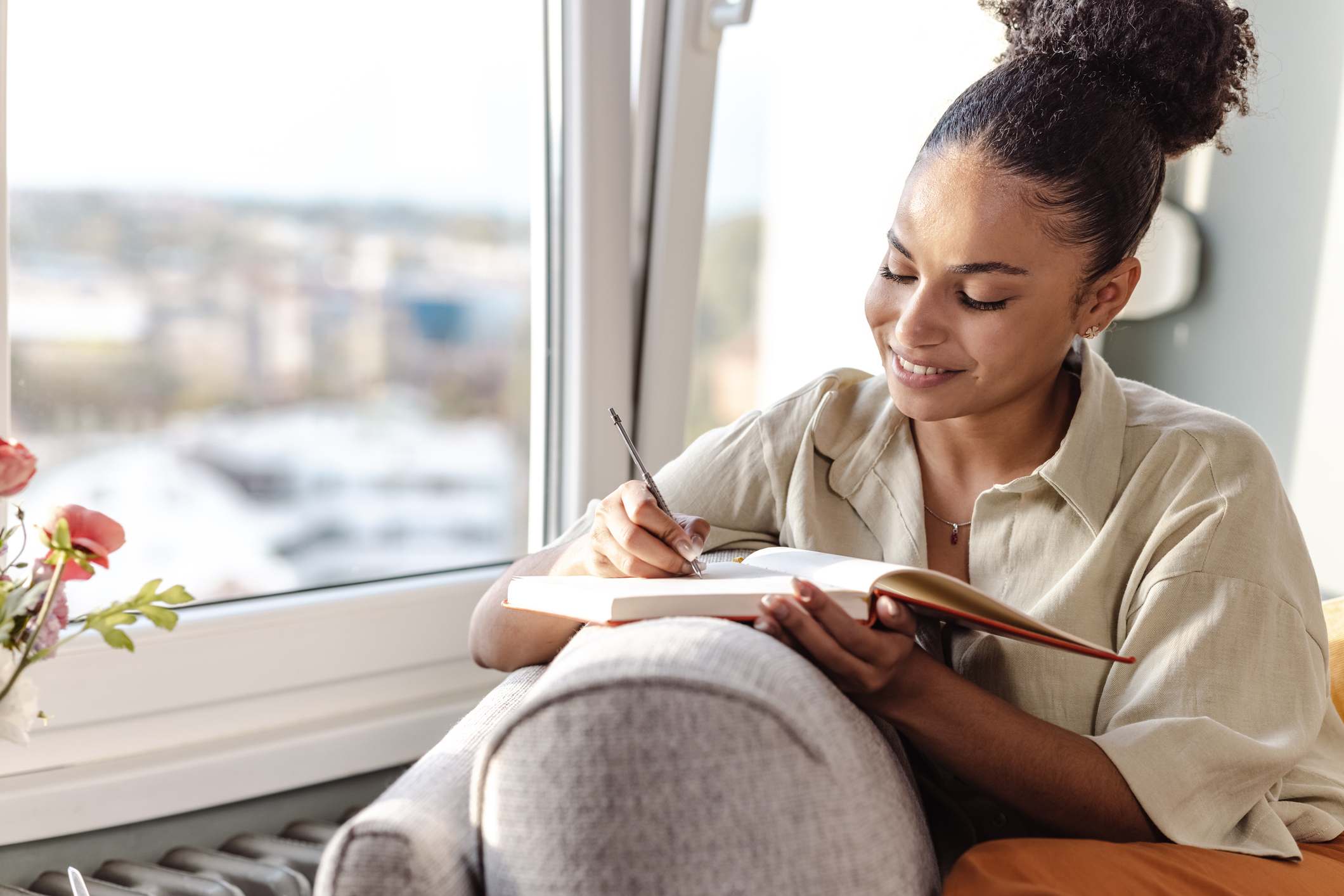 Woman-writing-in-her-journal-smiling-at-home-how-to-improve-self-determination