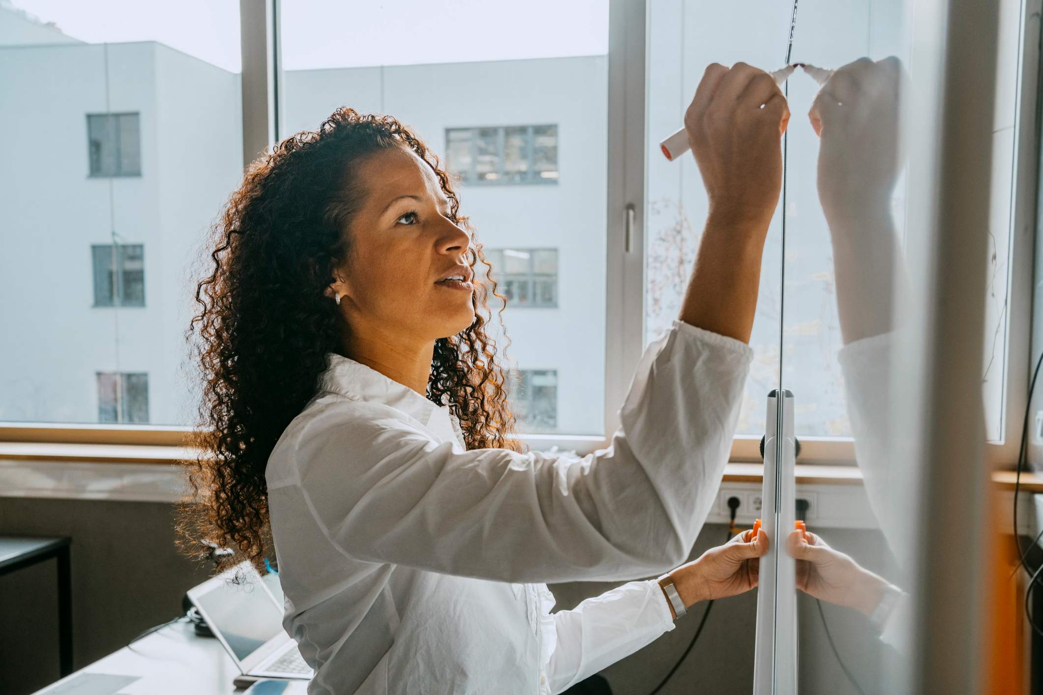 Woman-writing-something-on-whiteboard-what-makes-a-great-coach