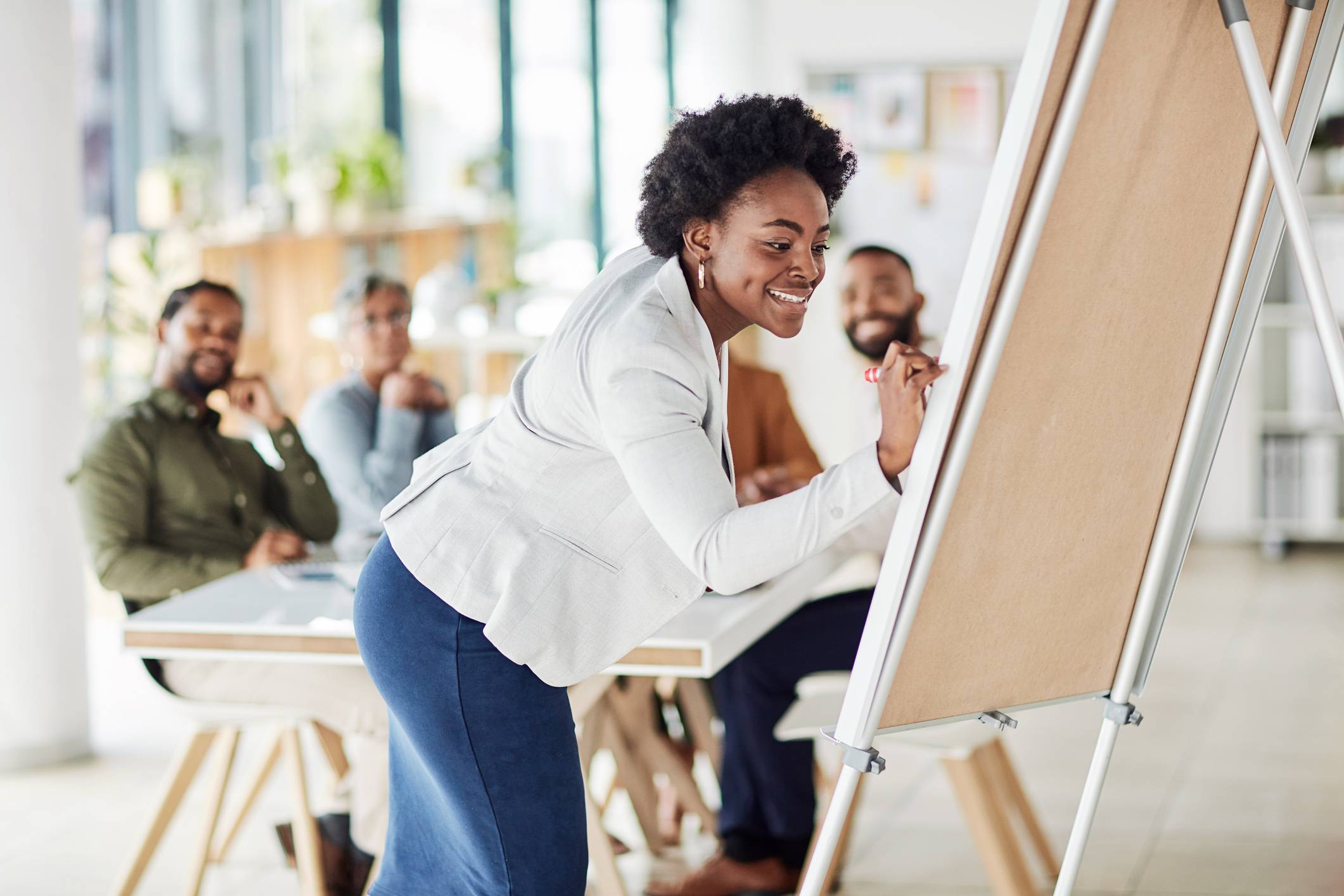 Woman-writing-task-in-white-board-for-her-team-types-of-leadership-styles