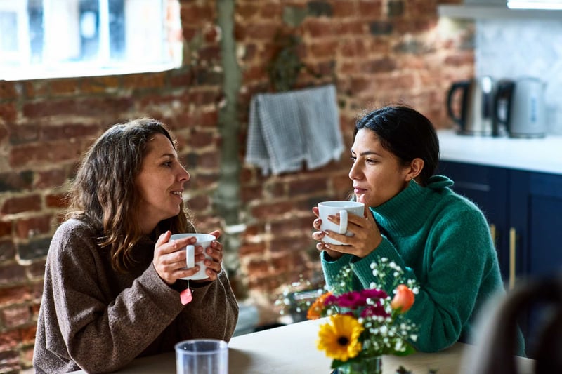 Women-enjoying-hot-drink-having-conversationTwo-friends-outside-coffee-shop-what-are-friendship-goals