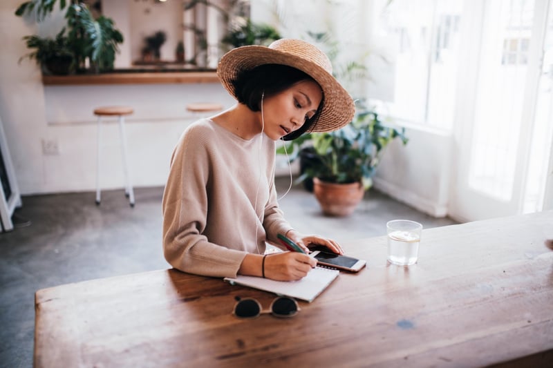 Young-Asian-Woman-Writing-Notes-In-Cafe