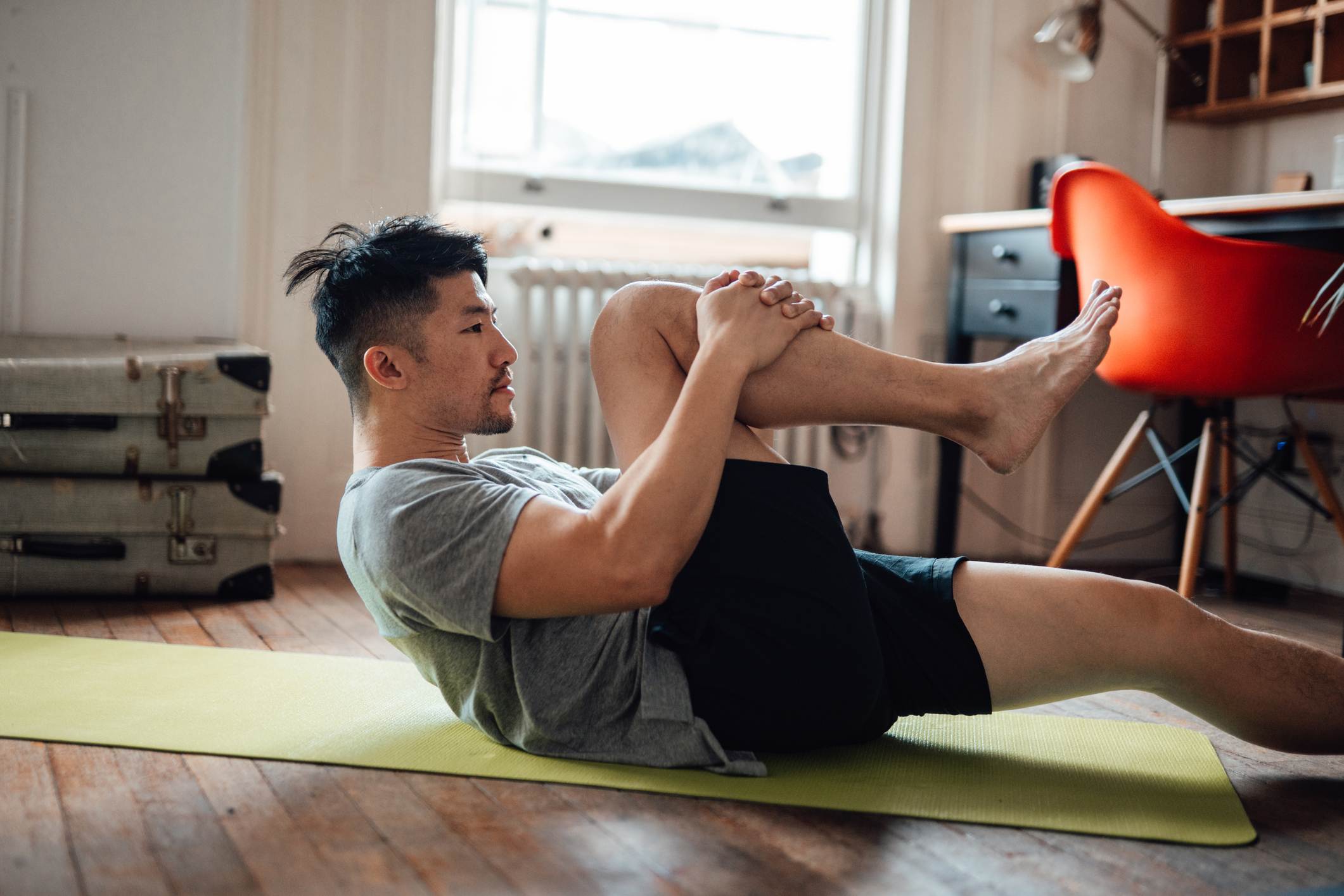 Young-Asian-man-stretching-during-workout-on-exercise-mat-at-home-how-improving-your-concentration-helps-your-memory