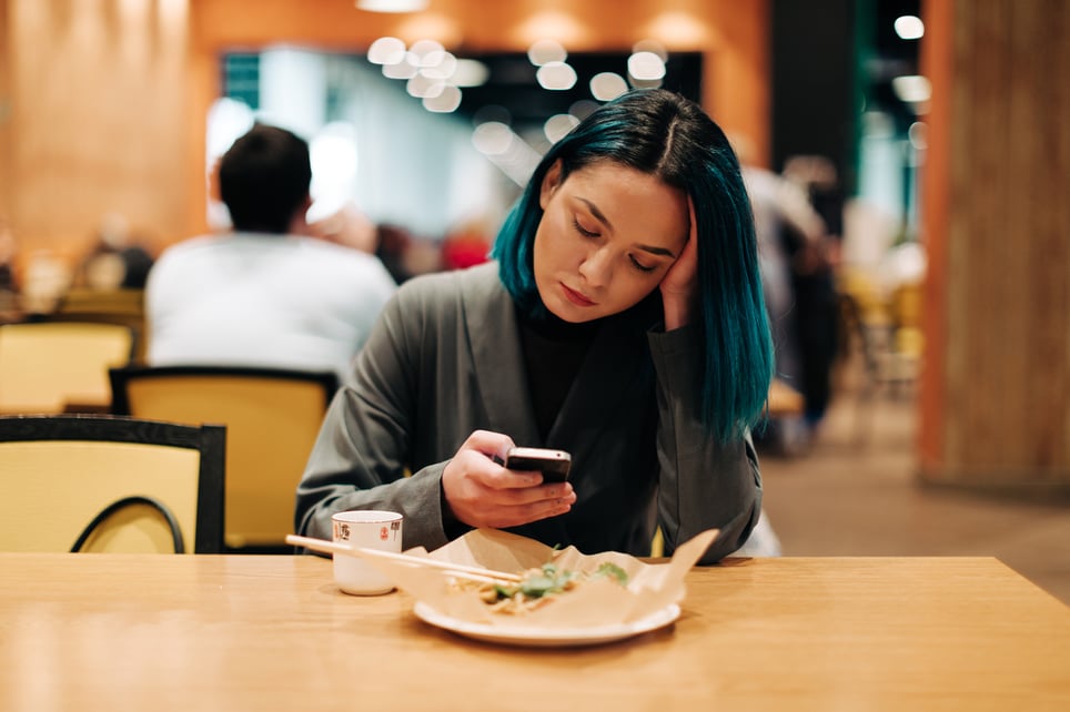 Young-Woman-On-The-Phone-Eating-At-Restaurant-phone-anxiety