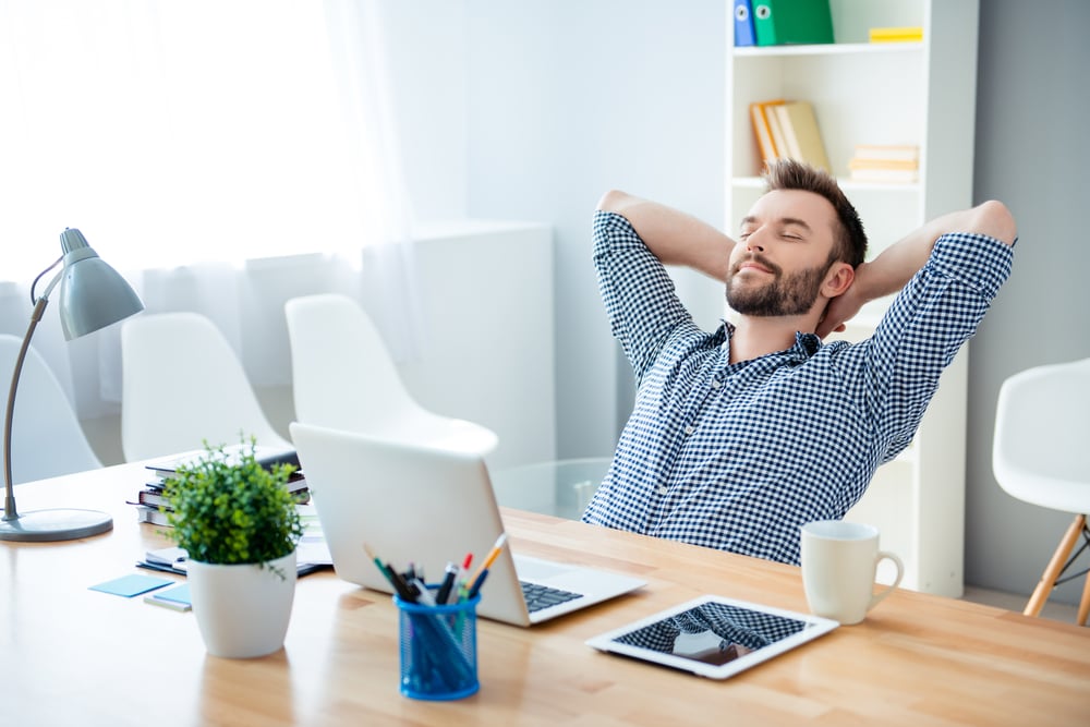 Young-businessman-leaning-on-his-desk-bored-at-work