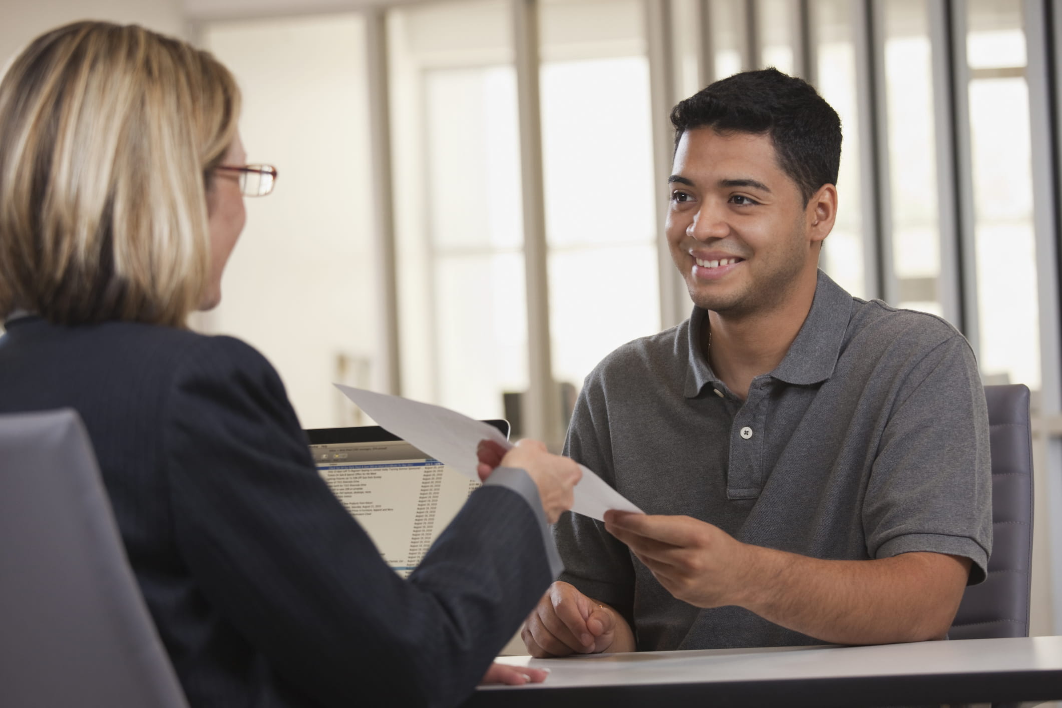 Young-man-handing-paper-to-older-executive-letter-of-intent