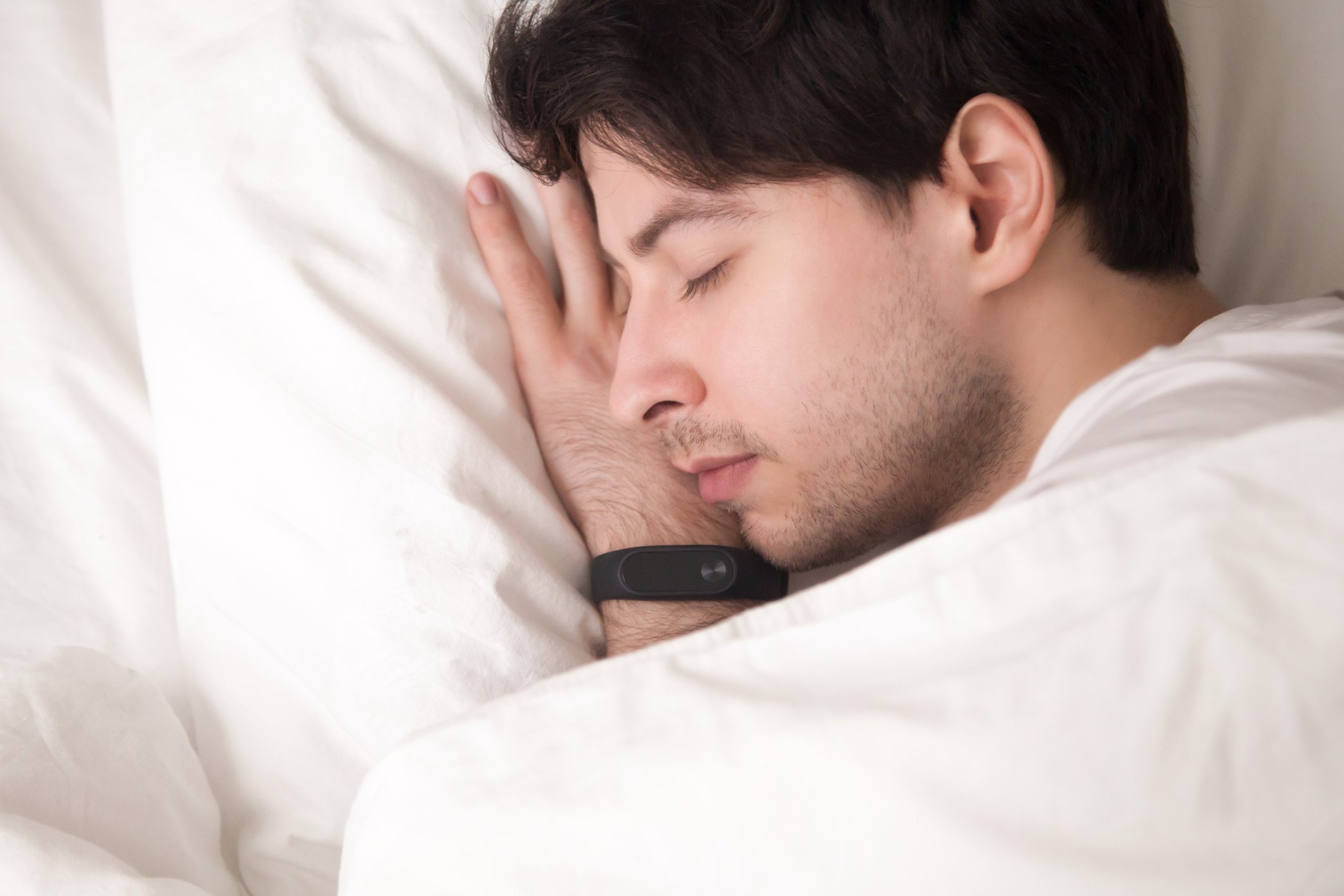 Young-man-is-asleep-and-wristband-tracking-his-sleep-how-to-sleep-earlier