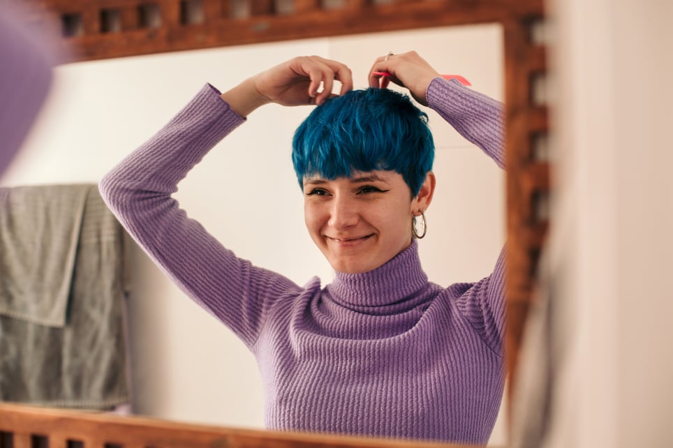 Young-woman-with-blue-hair-smiling-at-mirror-how-to-improve-self-esteem