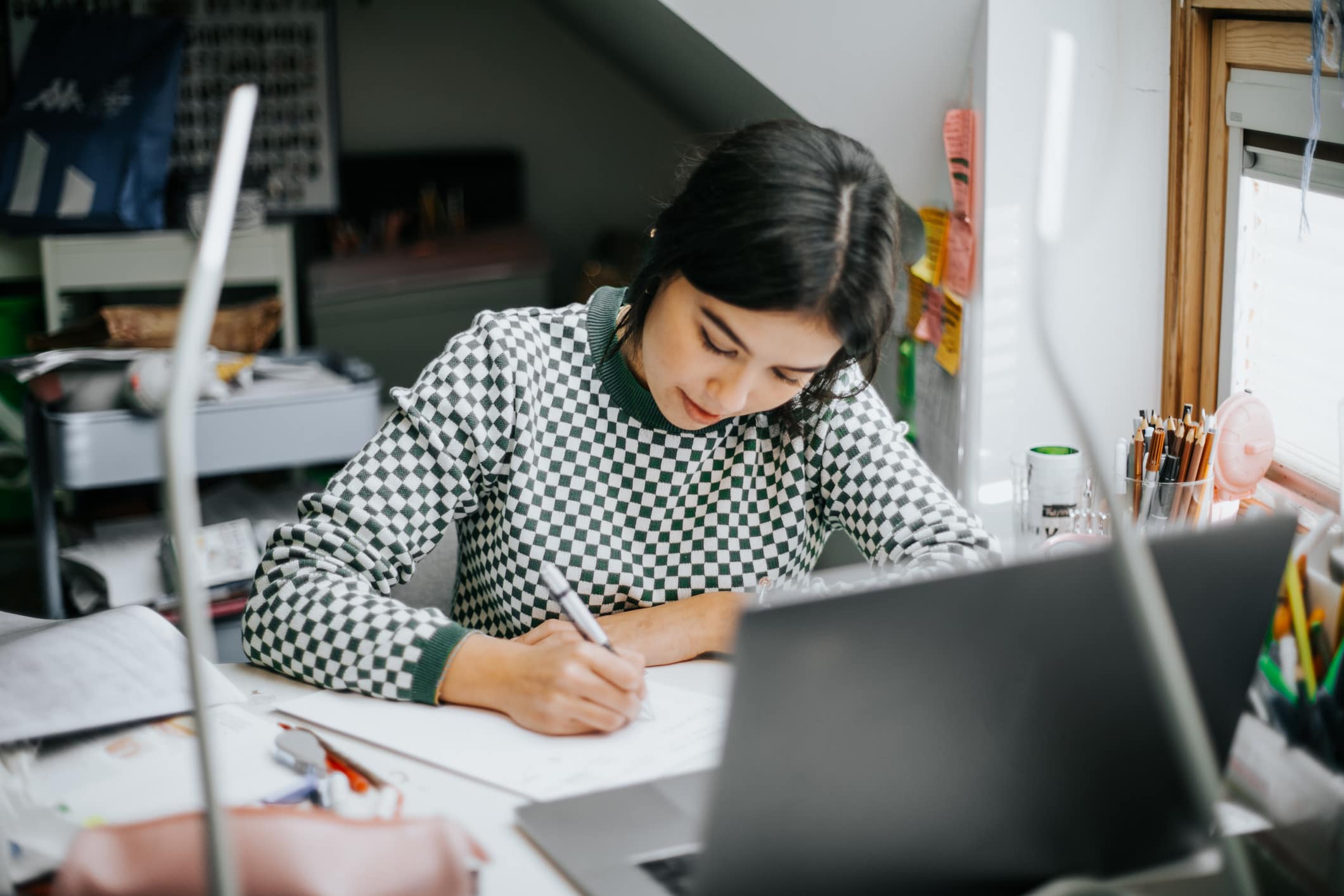 Young-woman-writing-intently-at-home-letter-of-intent