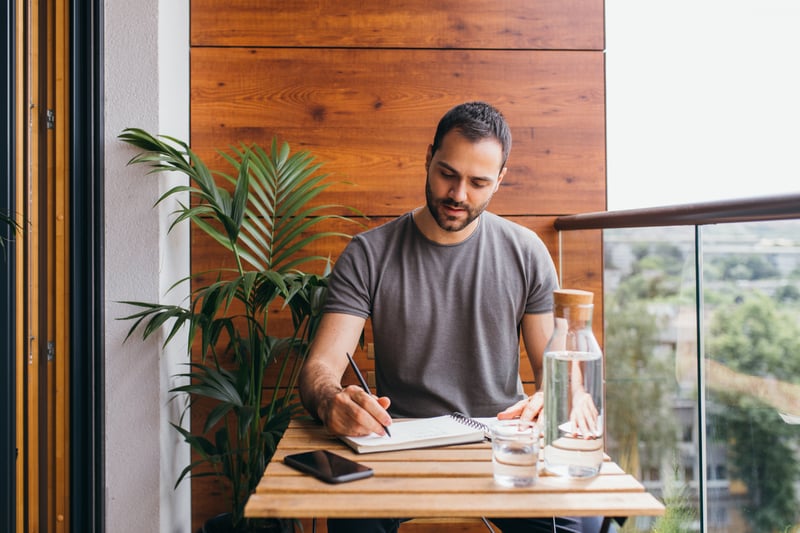 Youngiman-working-from-home——with-bottle-of-water-and-notebook