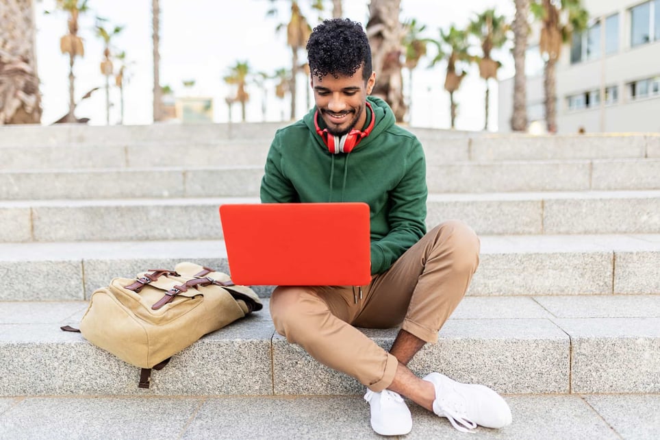 afro-man-with-green-hoodie-working-on-orange-laptop-working-as-a-contractor-vs-employee