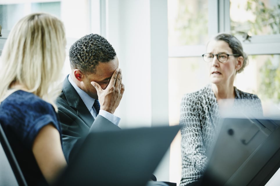 businessman-with-head-in-hand-during-meeting-distress-vs-eustress