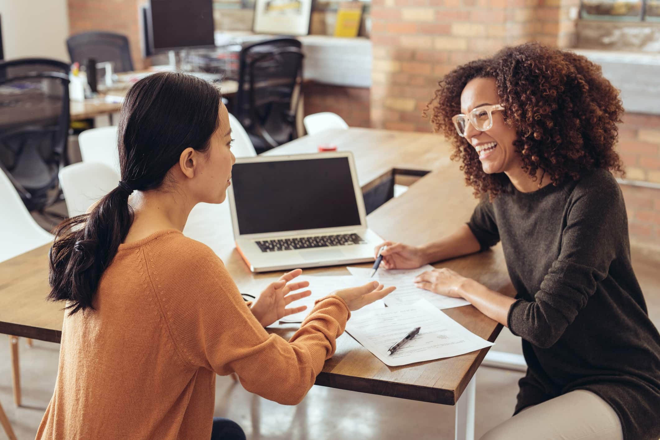 couple-of-colleagues-talking-on-desk-offer-acceptance-email