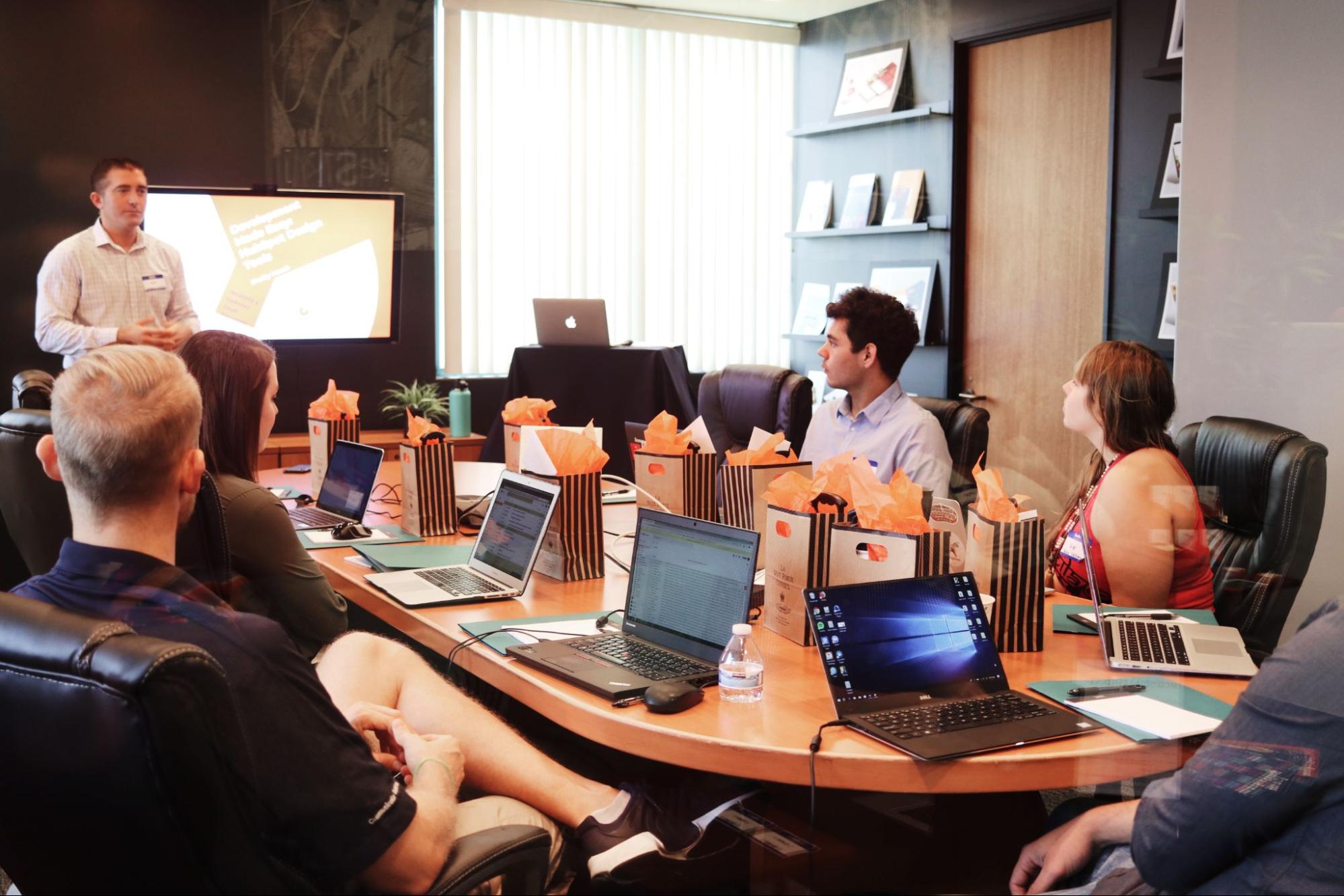 group-of-people-sit-around-a-table-with-laptops-in-a-work-meeting-executive-development