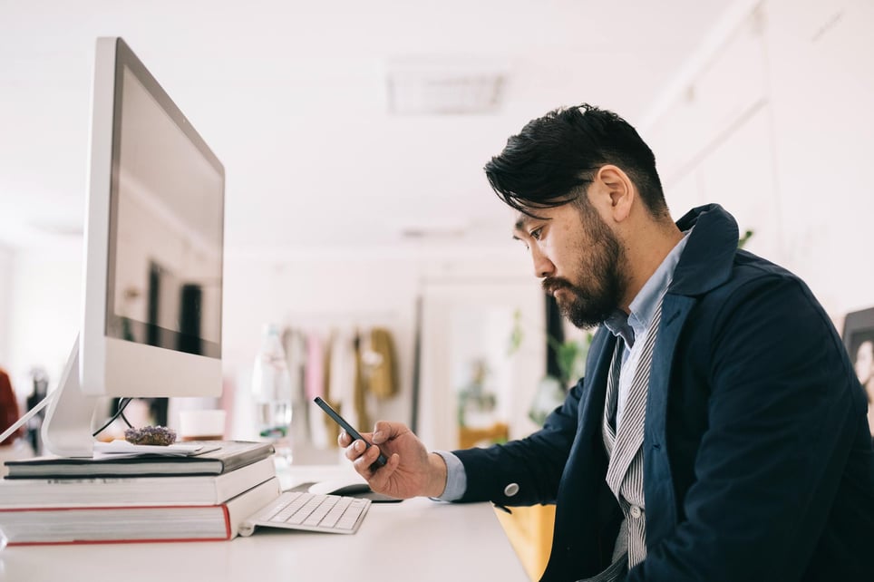 man-looking-at-his-phone-at-work-what-is-the-two-minute-rule