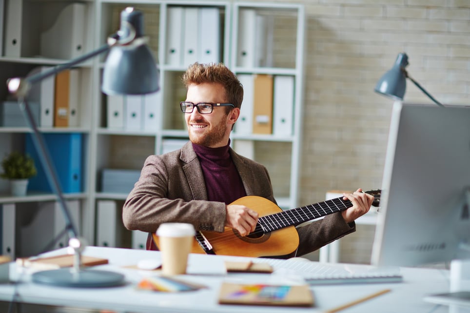 man-playing-his-guitar-at-work-self-care-and-work-life-balance