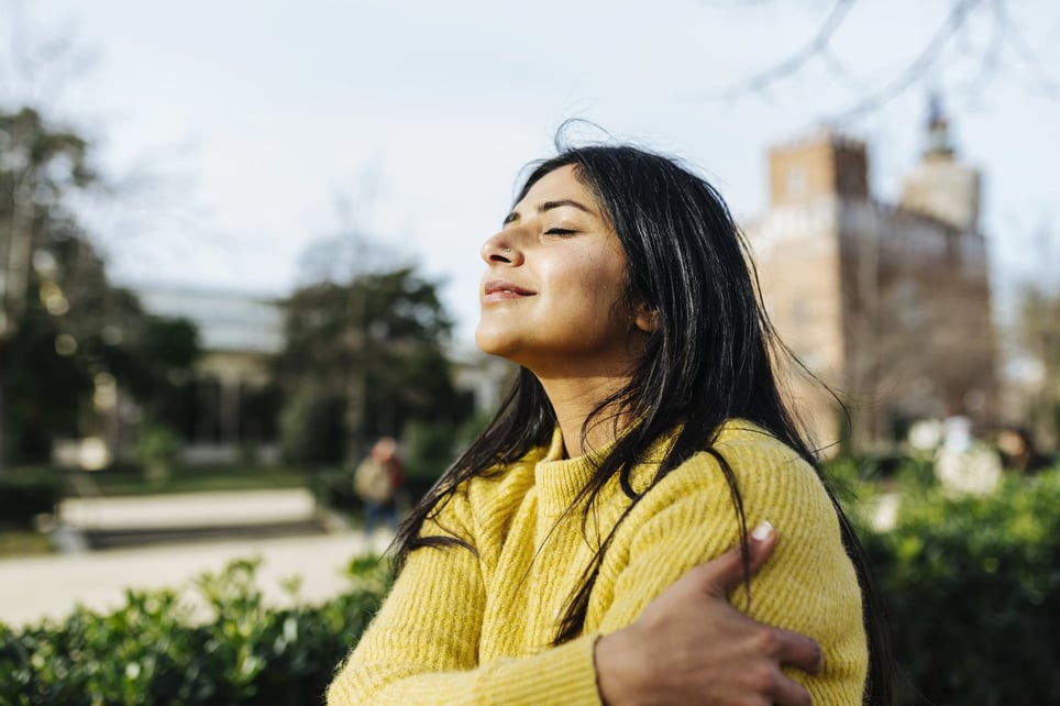 smiling-woman-hugging-self-against-sky