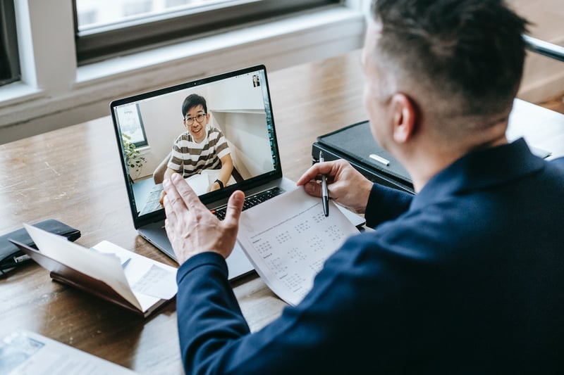 two-men-talking-and-looking-at-papers-on-videocall-virtual-interview