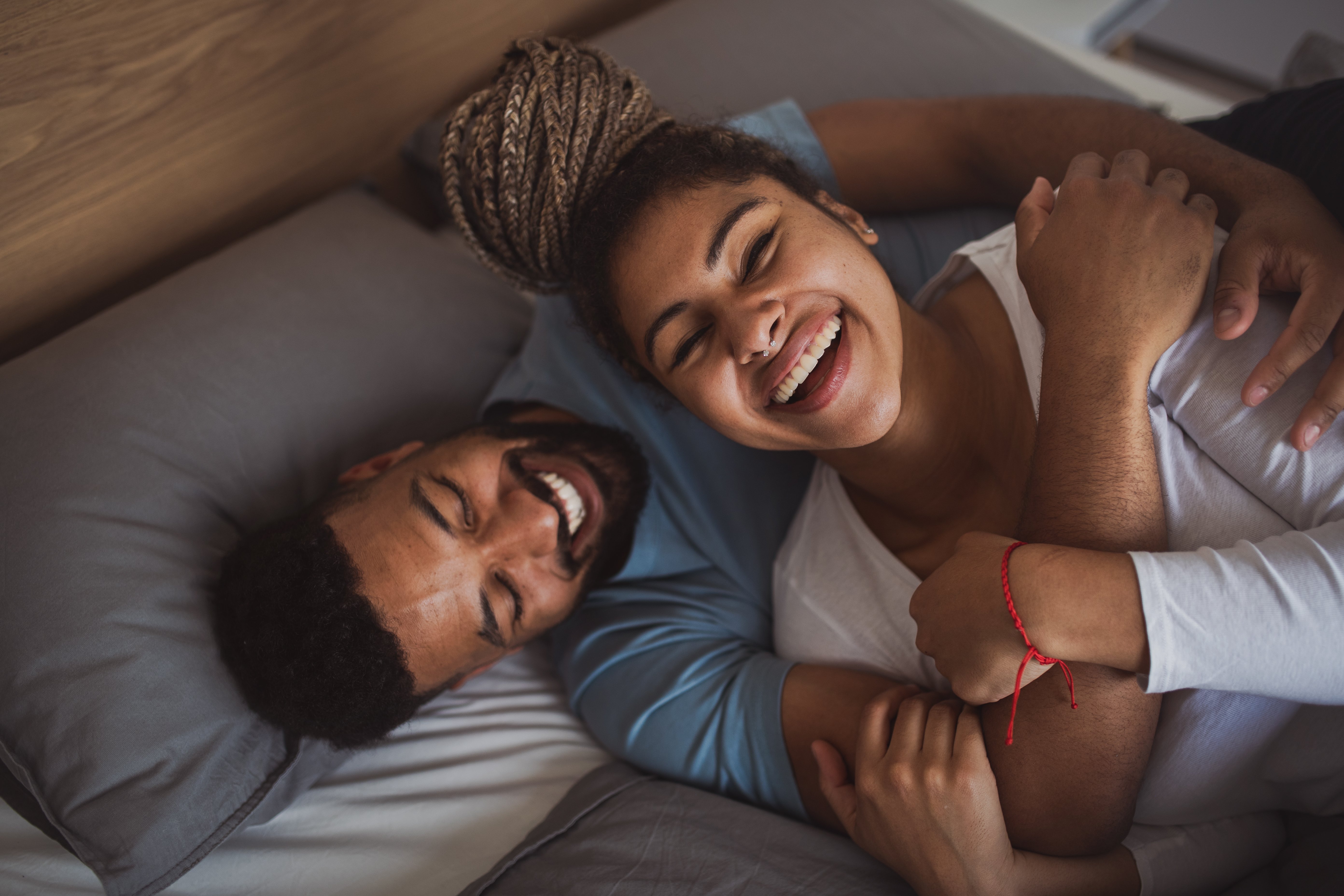 two-people-laughing-in-bed-sleep-hygiene