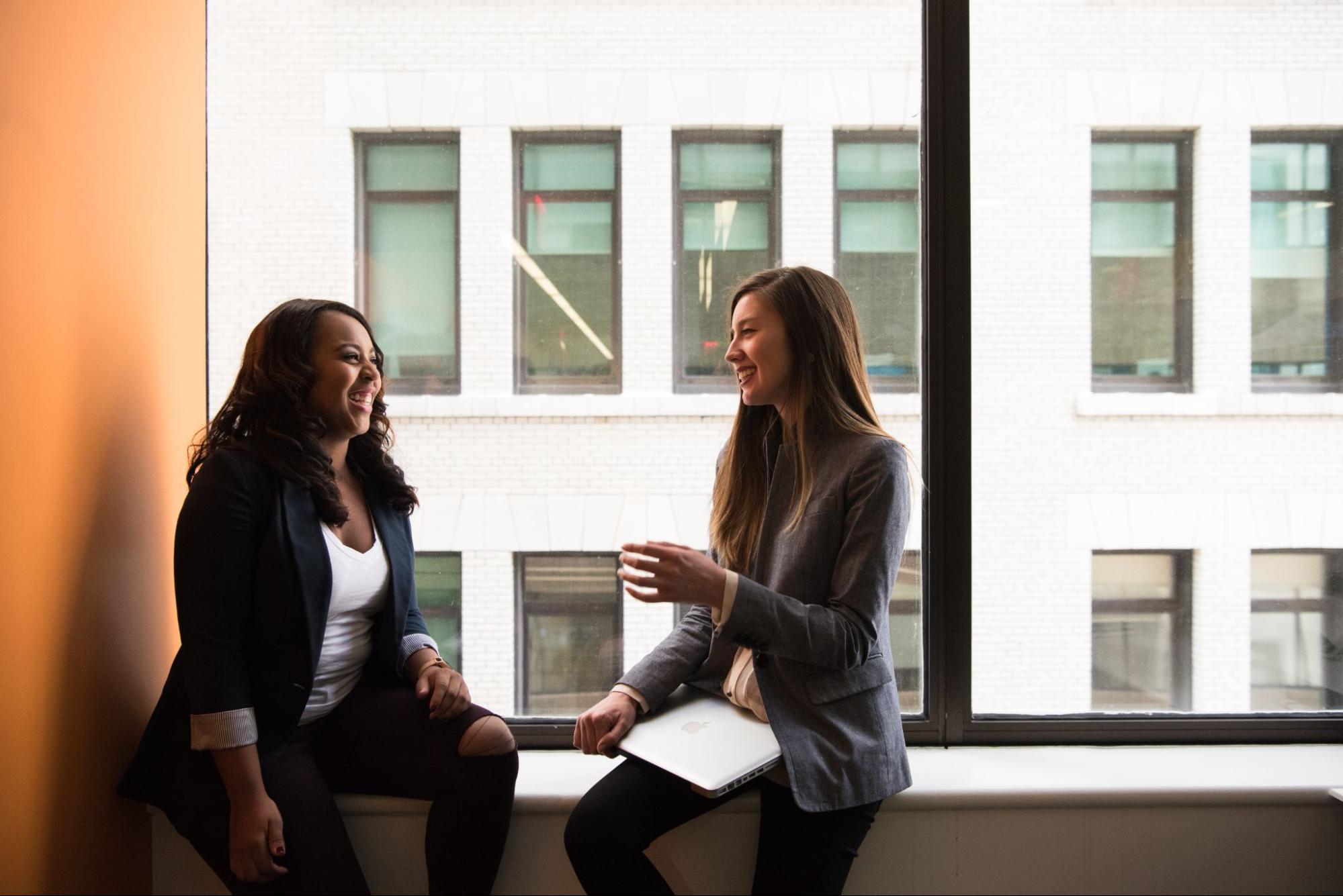 two-women-sit-in-windowsill-laughing-executive-development