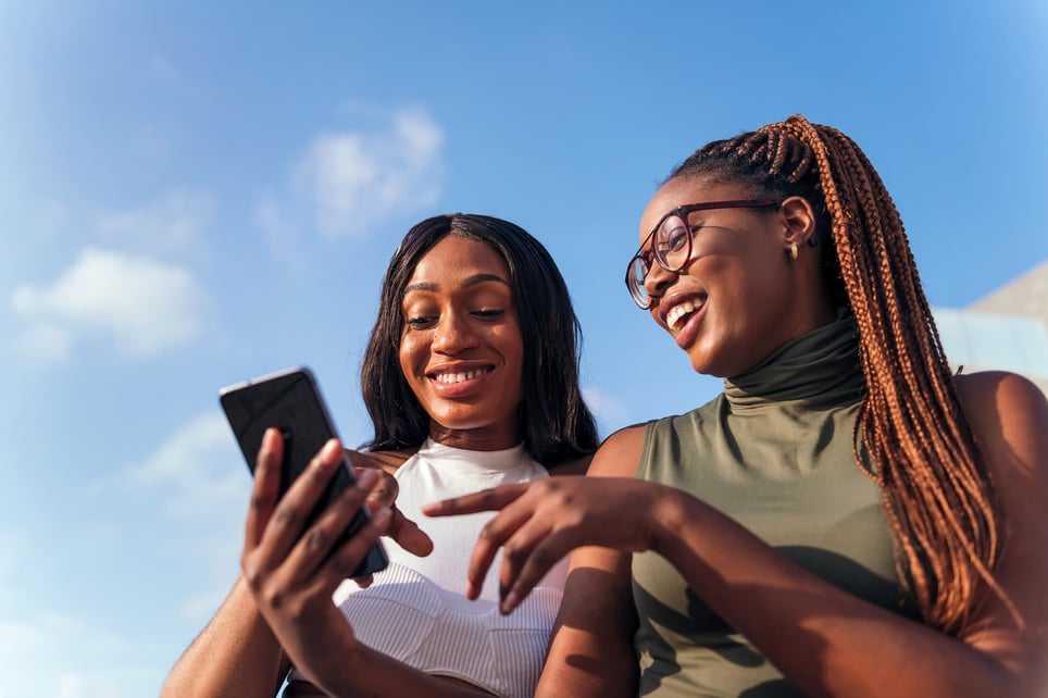 two-young-afro-women-having-fun-looking-at-the-cell-phone-how-to-make-friends-online