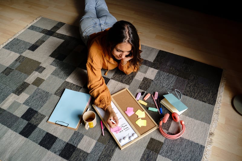 woman-lying-prostate-on-the-floor-planning-weekly-schedule-and-talking-by-phone-in-living-room