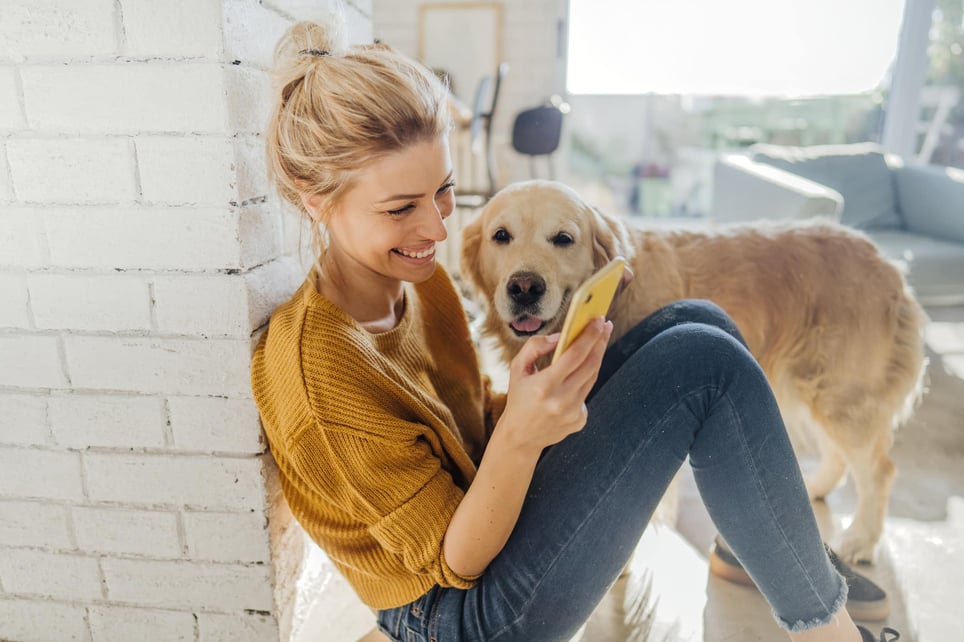 young-woman-looking-at-her-phone-with-her-dog-by-her-side-how-to-make-friends-online