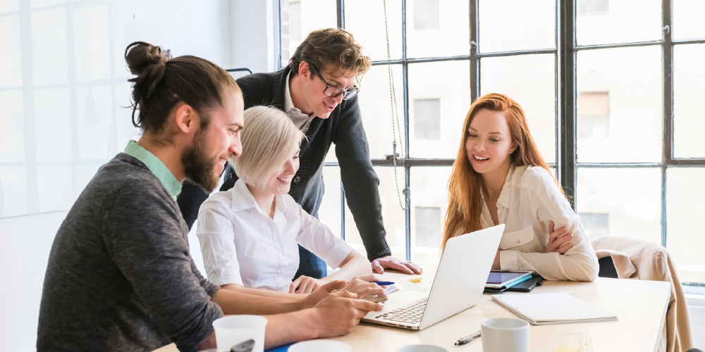 工作场所4-coworkers-gathered-around-computer-develop-leaders-for 2021 -